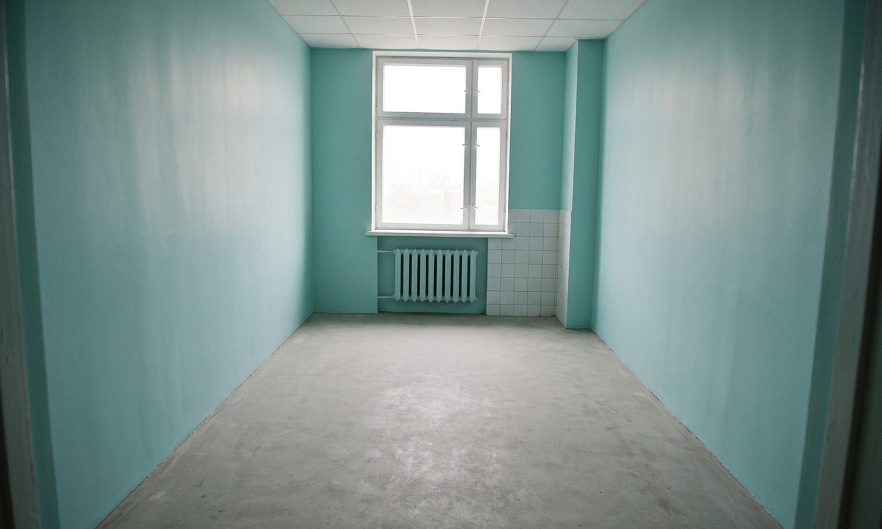 Derselbe Raum nach der Grundreinigung: gestrichene Wände, freier Estrichboden, saubere Fensterbank und Heizkörper.